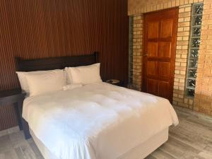 a large bed with white sheets and a wooden door at Happy Holiday Lodge in Meer en See +9 photos