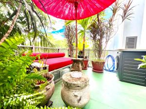 a patio with a red umbrella and some plants at Brianna Balcony Apartment in Ban Ton Chok