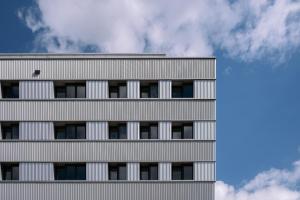 a tall grey building with a sky in the background at Hôtel Les Loges in Geneva