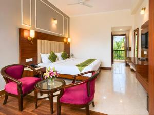 a hotel room with a bed and a table and chairs at juSTa Riverside Resort Srinagar in Devaprayāg