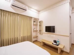 a bedroom with a bed and a tv and a bench at Parthas Suites in Tiruchirappalli