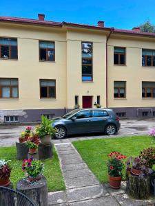 a car parked in front of a building with flowers at Baumanis klasika in Valmiera