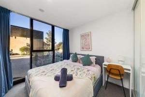 a bedroom with a bed and a desk and a window at 2BR-1BR-1Car- CBD Pool Central in Canberra