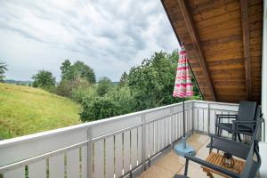 a porch with two rocking chairs and a flag at Ferienwohnung "Am Hennenberg" in Erlenmoos
