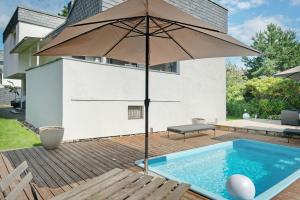 an umbrella sitting on a deck next to a swimming pool at Modern House, Pool, Garden in Burgdorf