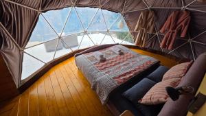 a room with a bed in a tent with a large window at Glamping ZAZEN in Drumu Carului