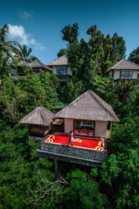 a woman is standing in front of a house at Hanging Gardens of Bali in Payangan