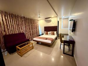 a bedroom with a bed and a couch and a table at Astra Hotels and Suites HSR Sector 1 in Bangalore