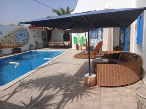 an umbrella and chairs next to a swimming pool at Dar Cally Maison d Artiste in Midoun