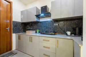 a kitchen with white cabinets and a sink at Soothing Stayz - Near Medanta The Medicity in Gurgaon
