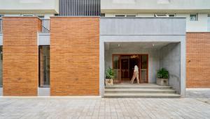 a person walking into a building with a brick wall at Parthas Suites in Tiruchirappalli