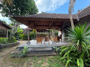 a pavilion with a table and chairs in a garden at Sarini Joglo Villa by Manara in Blahbatu
