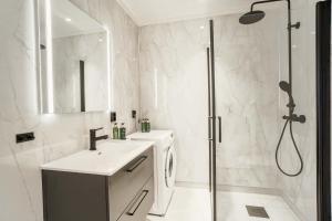 a white bathroom with a shower and a sink at Moderne leilighet i Gjøvik 201 in Gjøvik +5 photos