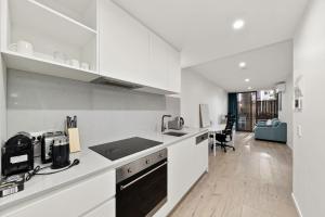 a kitchen with white cabinets and a counter top at 2B-1BR-1Car-Courtyard-CBD-Shops in Canberra +15 photos