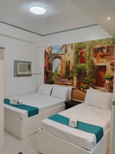 two beds in a room with a painting on the wall at Villa Adela Pension House in Balamban