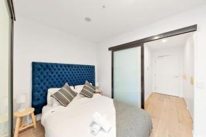 a bedroom with a large bed with a blue headboard at Central CBD - parking - sleeps 4 in Canberra