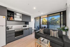 a living room with a gray couch and a kitchen at Central CBD - parking - sleeps 4 in Canberra