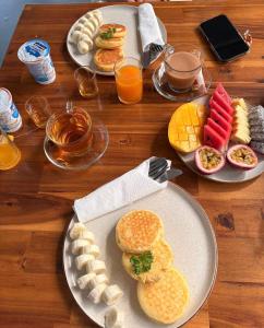 a wooden table with plates of breakfast foods and drinks at Cosy Garden Khao Sok in Khao Sok National Park