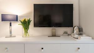 a television on a white cabinet with a vase of flowers at Deki Relais in Sassari