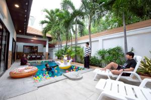 a group of people sitting around a pool in a house at MM Pool Villa in Pattaya South