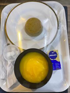a plate with a bowl of mustard and a piece of bread at St Kora Apartment and Shortlets in Asaba