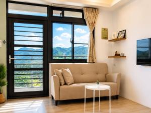 a living room with a couch and large windows at 若家民宿 台東縣民宿1275號 in Guanshan