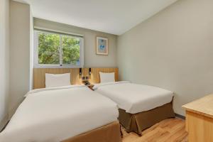 two beds in a small room with a window at Whiyori Inn in Kaohsiung