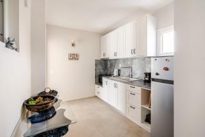 a kitchen with white cabinets and a bowl of fruit on a table at GAIAeMARE Suit Apartment in Pesádha