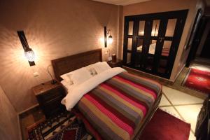 a bedroom with a bed with a colorful blanket and a window at Riad Dar Haven in Tamraght Ou Fella