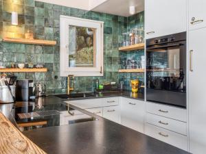 a kitchen with white cabinets and green tiles at Luxury Alpine Chalet with incredible Views in Lenk
