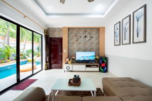 a living room with a couch and a tv at MM Pool Villa in Pattaya South