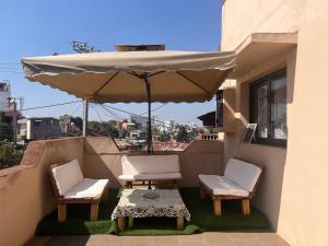 a patio with two chairs and a table and an umbrella at Akany Fitahiantsoa in Ivato
