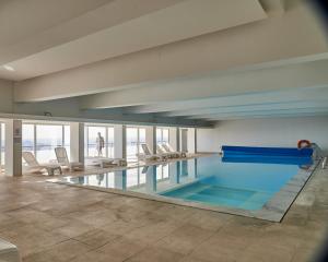 a swimming pool in a building with chairs in it at Alfândega da Fé Hotel & SPA in Sambade