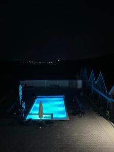 a swimming pool at night with a person standing next to it at La Luna Imobiliare in Ocna-Mureşului