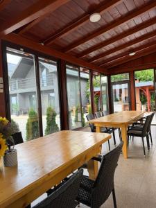 two wooden tables and chairs in a room with windows at La Luna Imobiliare in Ocna-Mureşului