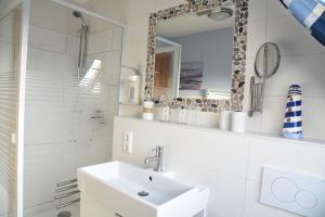 a white bathroom with a sink and a mirror at Ferienwohnung Ankerpladsen Opti in Behrensdorf +14 photos
