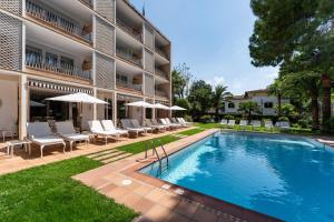 Ein Schwimmbad vor einem Gebäude mit Stühlen und Sonnenschirmen in der Unterkunft Hotel Araxa - Adults Only in Palma de Mallorca