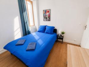 a blue bed in a bedroom with blue pillows on it at Centre-Ville Appartement 90m2 Le Normand in Elbeuf