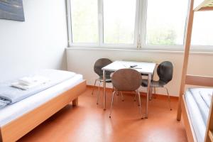a room with two beds and a table and chairs at Junges Hotel Hard am Bodensee in Hard