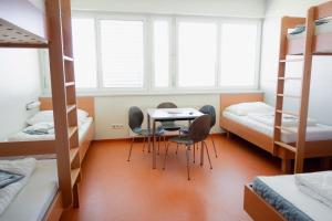 a room with a table and chairs and bunk beds at Junges Hotel Hard am Bodensee in Hard