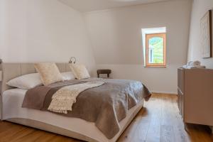 a white bedroom with a large bed and a window at Hakuna Rooftop Penthouse Wachau in Spitz