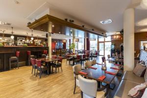a restaurant with tables and chairs and a bar at Dormio Hotel Obertraun in Obertraun