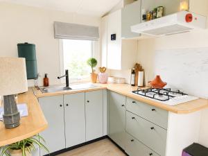 a kitchen with white cabinets and a sink at The Red Shutter Cottage in Hattemerbroek