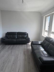 a black couch in a living room with a wooden floor at Glasgow Airport in Glasgow