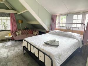 ein Schlafzimmer mit einem großen Bett und einer Couch in der Unterkunft d'oude hoeve in Rijsbergen