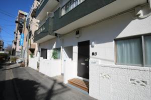 a white building with a black door and a wooden porch at QU302 EPrivate 2BR Home with Living Room and Kitchen, Separate Bath and Toilet, Sleeps 4 in Tokyo