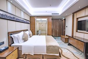 a bedroom with a large bed and a flat screen tv at Maoming International Hotel in Maoming