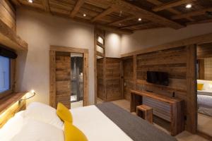 a bedroom with wooden walls and a bed and a tv at Au Coin Du Feu in Megève