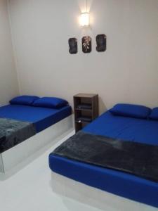 a bedroom with two beds and a night stand at Melor Guest house in Kampong Telok Dalam