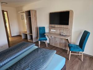 a hotel room with a bed and two chairs and a television at Hotel Felix in Mietingen